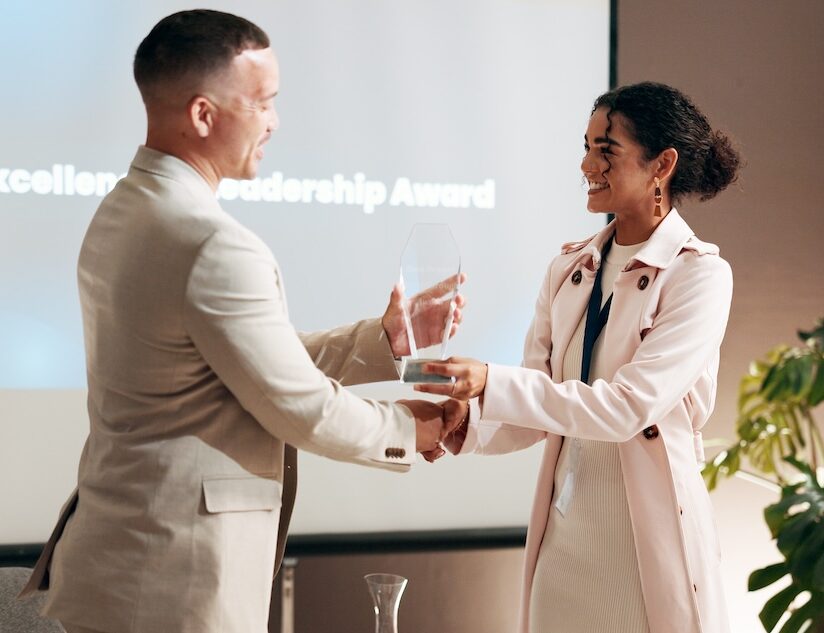 Trophy, presentation and success with business people at award ceremony for thank you, prize and wi.