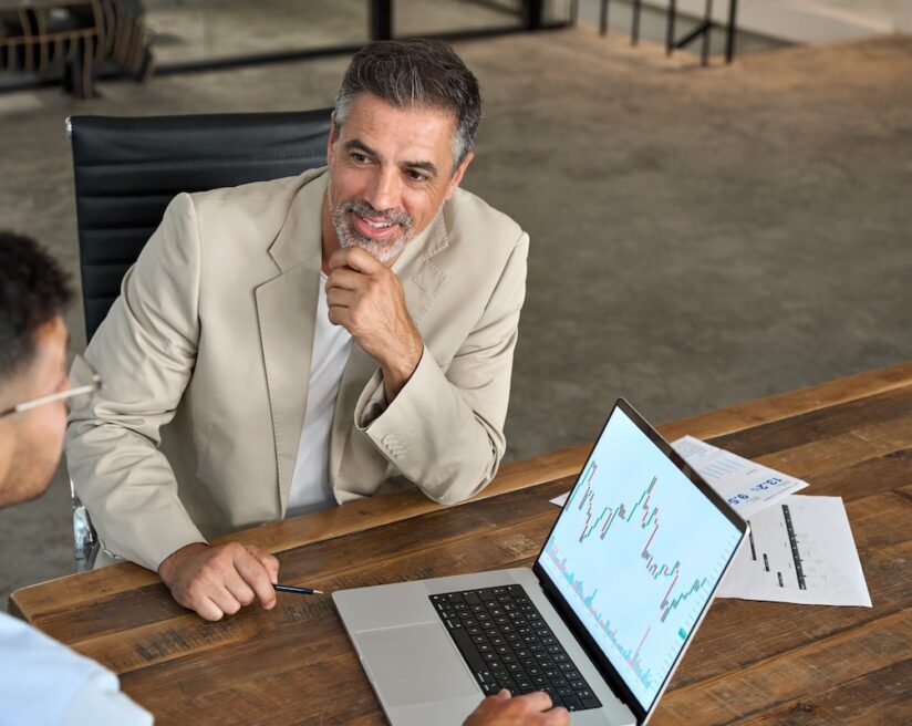 Professional advisor consulting business man investor explaining financial trade stock market trends in crypto exchange investing planning using laptop computer at office meeting. Copy space.